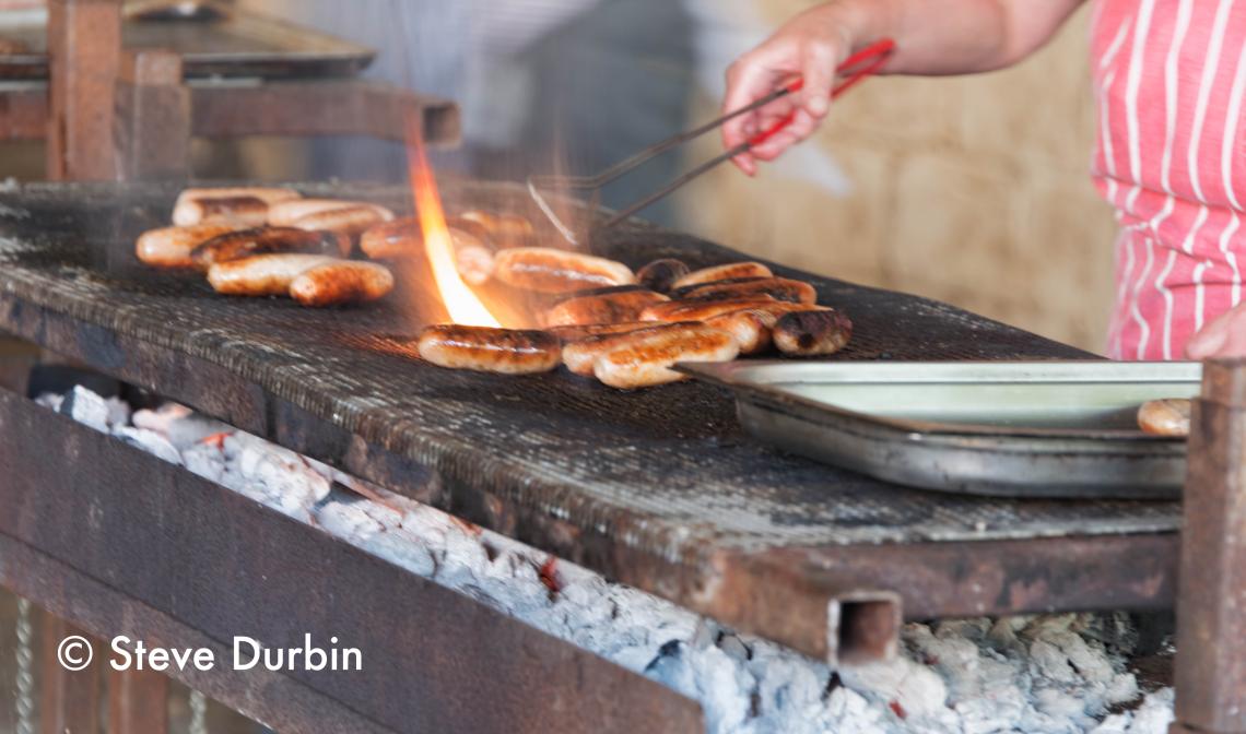 A BBQ, close up of sausages cooking.