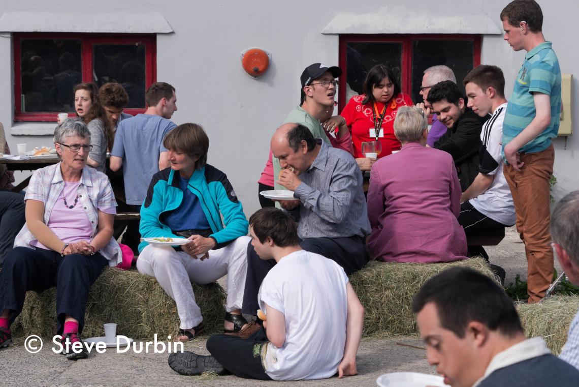 Families sat outside on straw bales at Elidyr Communities Trust.